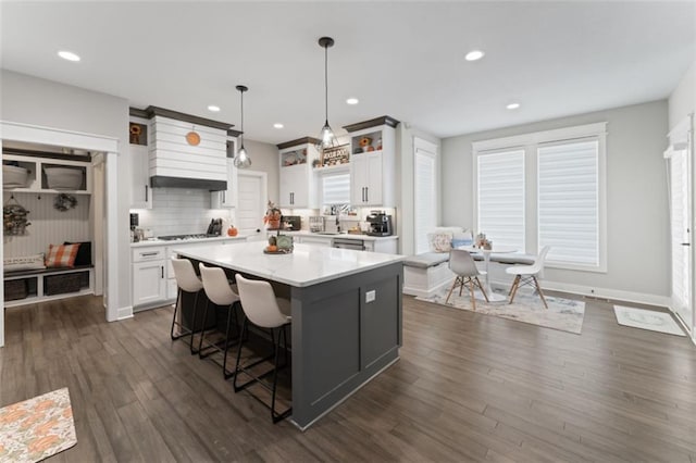 kitchen featuring decorative backsplash, dark hardwood / wood-style flooring, decorative light fixtures, white cabinets, and a center island