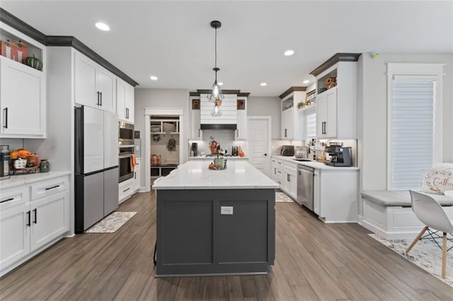 kitchen with dark wood-type flooring, pendant lighting, built in appliances, white cabinets, and a kitchen island