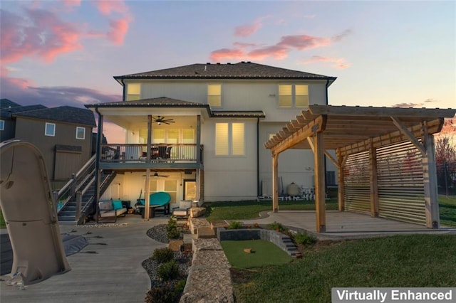 back house at dusk with ceiling fan, a pergola, a patio, and a wooden deck