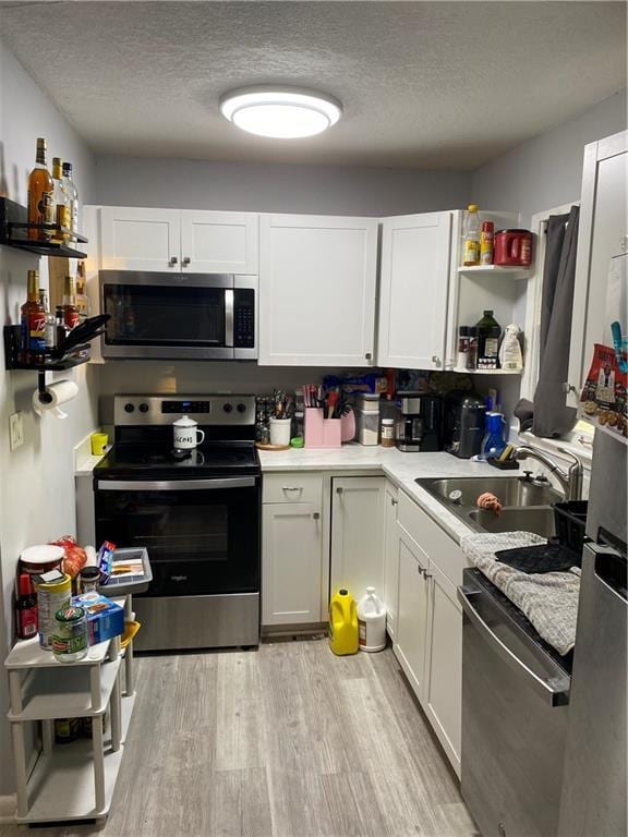 kitchen with white cabinetry, appliances with stainless steel finishes, and light hardwood / wood-style flooring