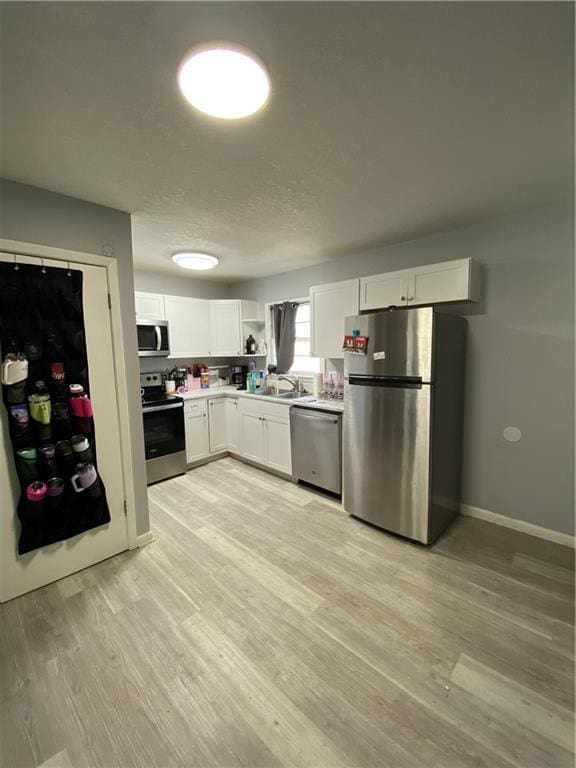 kitchen featuring white cabinetry, light hardwood / wood-style flooring, stainless steel appliances, and sink