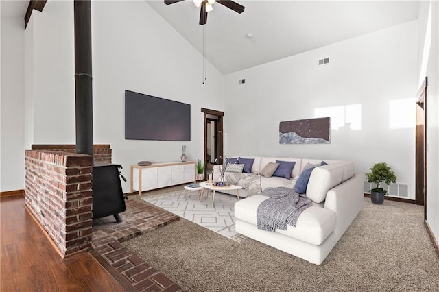 living room with a wood stove, ceiling fan, high vaulted ceiling, and hardwood / wood-style flooring