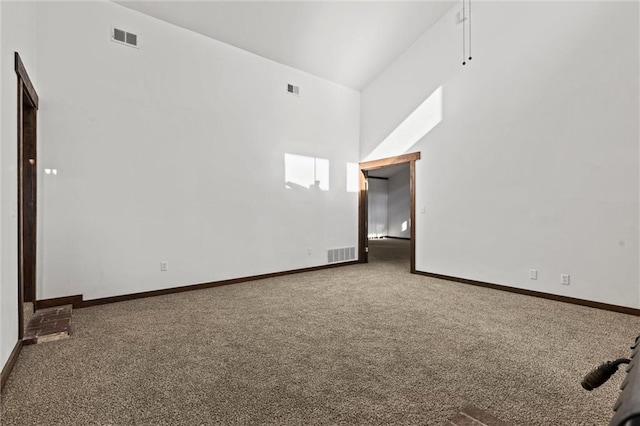 carpeted spare room featuring high vaulted ceiling