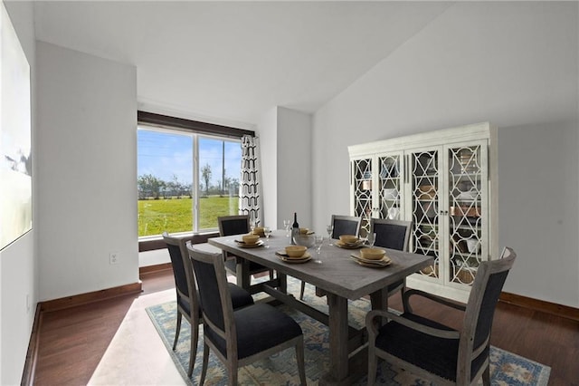 dining area featuring dark hardwood / wood-style flooring and vaulted ceiling