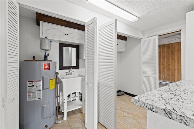 interior space featuring a textured ceiling, electric water heater, and light tile patterned floors