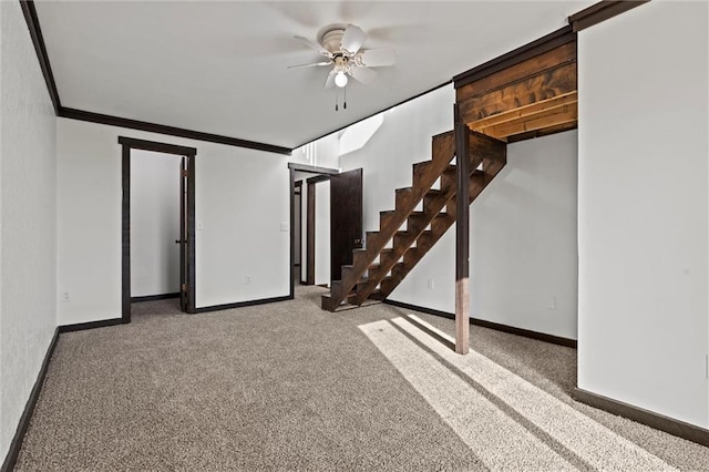 basement featuring ceiling fan, light colored carpet, and crown molding