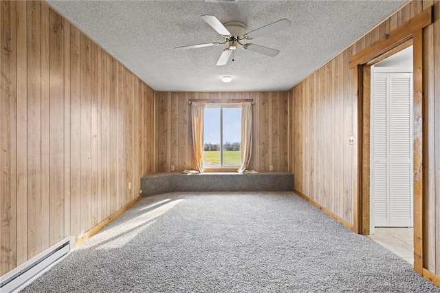 unfurnished room featuring a baseboard radiator, ceiling fan, wooden walls, and light colored carpet