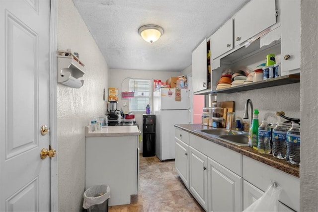 kitchen featuring white cabinetry, sink, a textured ceiling, and white refrigerator