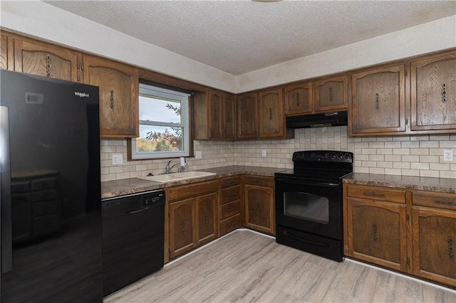 kitchen with backsplash, a textured ceiling, sink, black appliances, and light hardwood / wood-style flooring