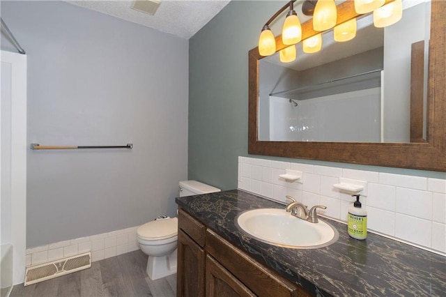 bathroom featuring decorative backsplash, toilet, a textured ceiling, walk in shower, and wood-type flooring