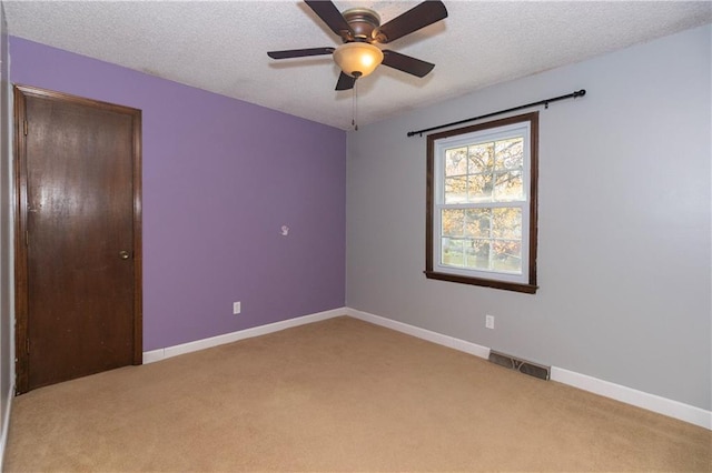 unfurnished room featuring a textured ceiling, ceiling fan, and light carpet