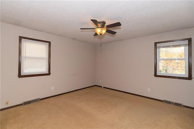 unfurnished room featuring ceiling fan, light colored carpet, and a textured ceiling