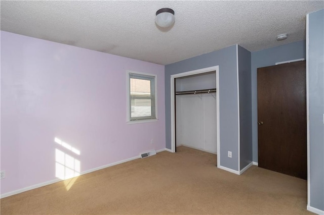 unfurnished bedroom with a textured ceiling, light colored carpet, and a closet