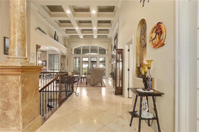 hall with a high ceiling, french doors, ornate columns, ornamental molding, and beam ceiling