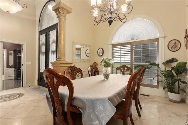 tiled dining space featuring an inviting chandelier, a towering ceiling, and decorative columns