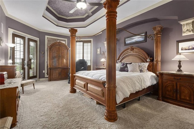 carpeted bedroom featuring access to exterior, decorative columns, a raised ceiling, ceiling fan, and crown molding