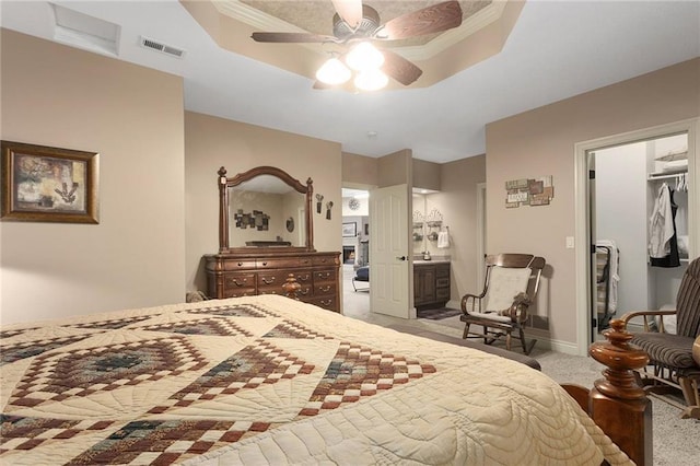 carpeted bedroom featuring ensuite bathroom, a closet, a tray ceiling, and ceiling fan