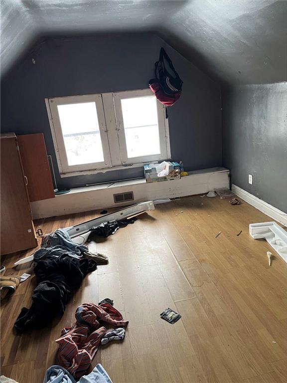 additional living space featuring lofted ceiling, visible vents, baseboards, and wood finished floors