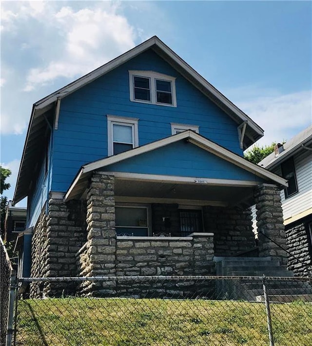 view of front of home with stone siding and fence