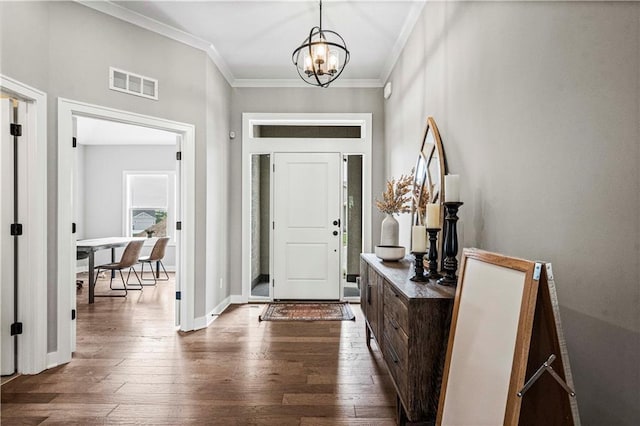 entryway with a notable chandelier, wood-type flooring, and crown molding