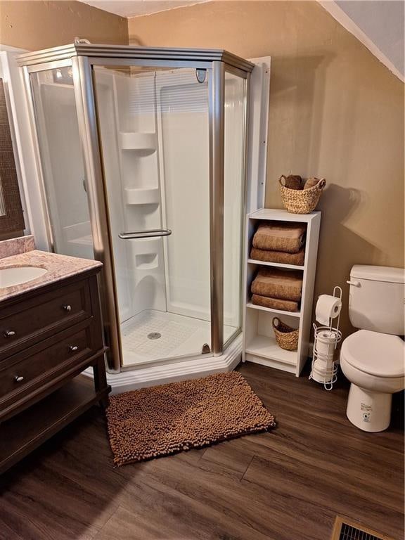 bathroom with hardwood / wood-style floors, vanity, toilet, and walk in shower