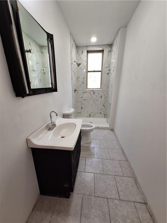 bathroom with a tile shower, vanity, and toilet