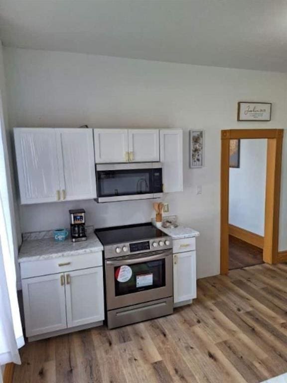 kitchen with appliances with stainless steel finishes, light wood-type flooring, and white cabinetry