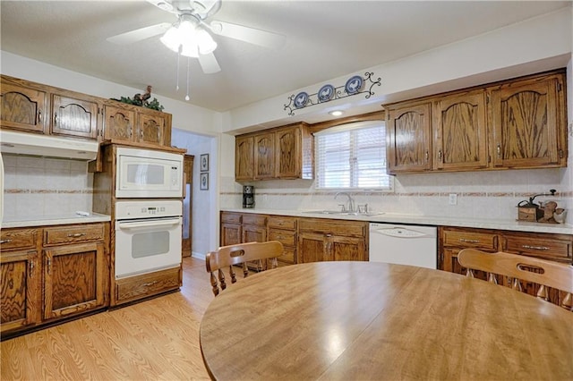 kitchen with sink, decorative backsplash, white appliances, ceiling fan, and light wood-type flooring