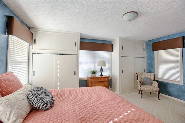 carpeted bedroom with two closets and a textured ceiling