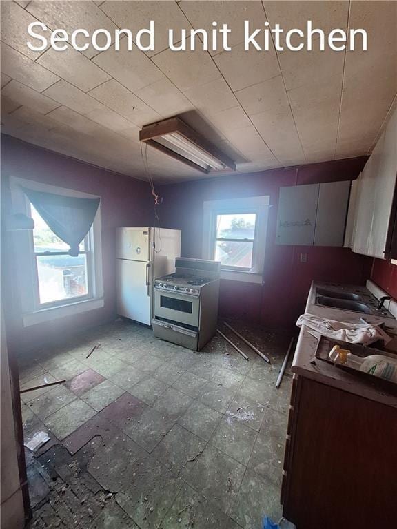 kitchen featuring white fridge, sink, and stainless steel range