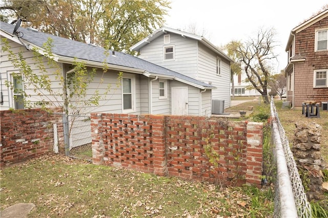 rear view of property featuring a yard and central AC unit