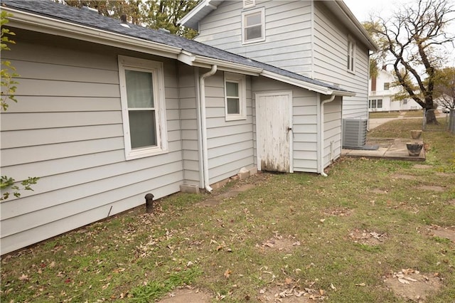 view of side of home with a lawn and central AC