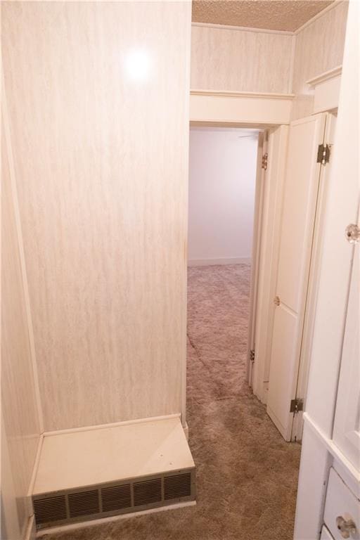 hallway featuring a textured ceiling and dark colored carpet