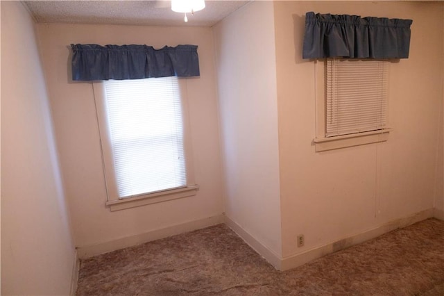 carpeted spare room featuring plenty of natural light and a textured ceiling