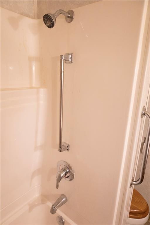 room details featuring toilet and washtub / shower combination