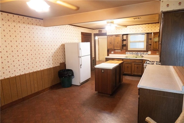 kitchen featuring wood walls, sink, a kitchen island, and white appliances