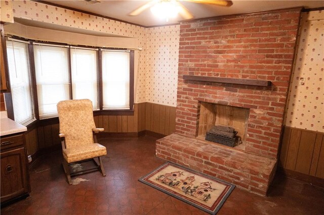 living area with ceiling fan, a fireplace, and wooden walls