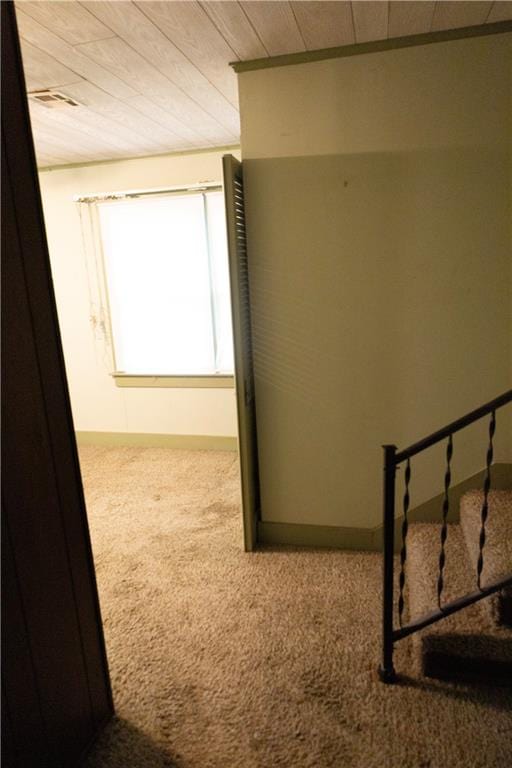 hallway featuring carpet flooring and wooden ceiling