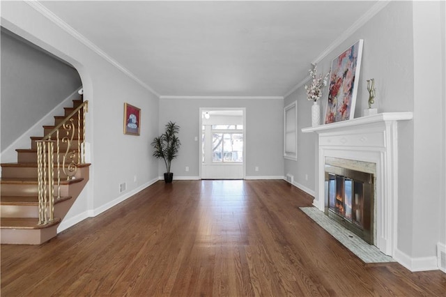 unfurnished living room featuring a high end fireplace, ornamental molding, and dark hardwood / wood-style floors