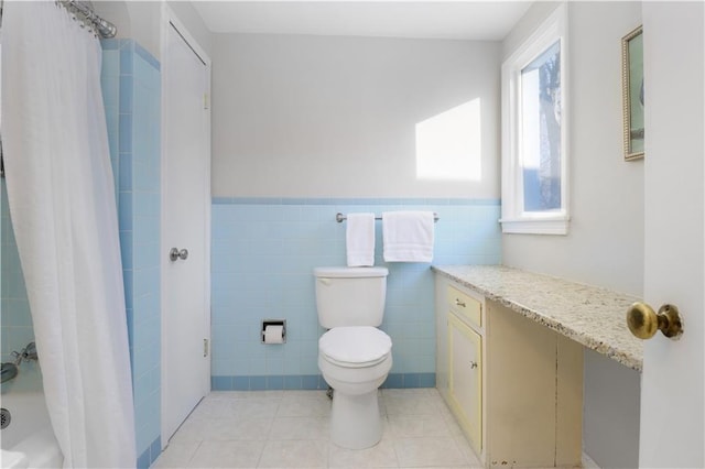 full bathroom featuring toilet, shower / bath combination with curtain, tile walls, tile patterned floors, and vanity