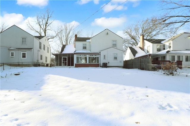 snow covered house featuring cooling unit and a sunroom