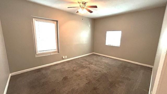 empty room featuring dark colored carpet, a wealth of natural light, and ceiling fan