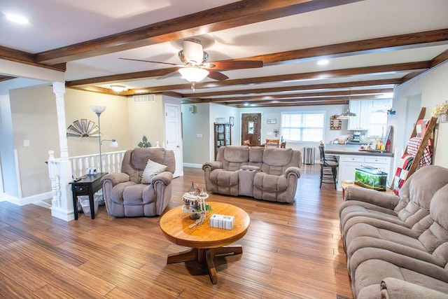 living room with beamed ceiling, ceiling fan, radiator, and light hardwood / wood-style flooring