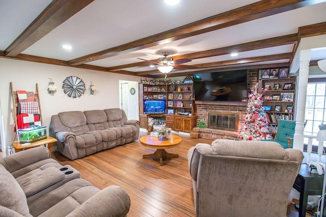 living room with beam ceiling, ceiling fan, light hardwood / wood-style flooring, and a brick fireplace