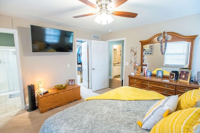 bedroom with ceiling fan, a spacious closet, light carpet, and a closet