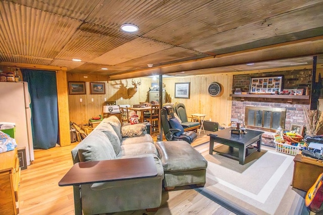 living room with wooden walls, a fireplace, and light wood-type flooring