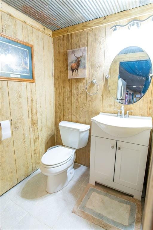 bathroom with vanity, toilet, and wood walls