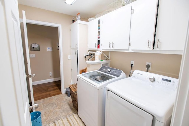 washroom featuring cabinets, washing machine and dryer, and light hardwood / wood-style flooring