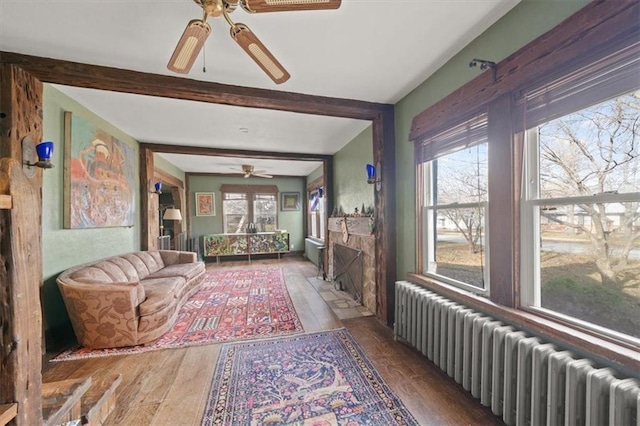 interior space with beamed ceiling, ceiling fan, radiator heating unit, and dark wood-type flooring