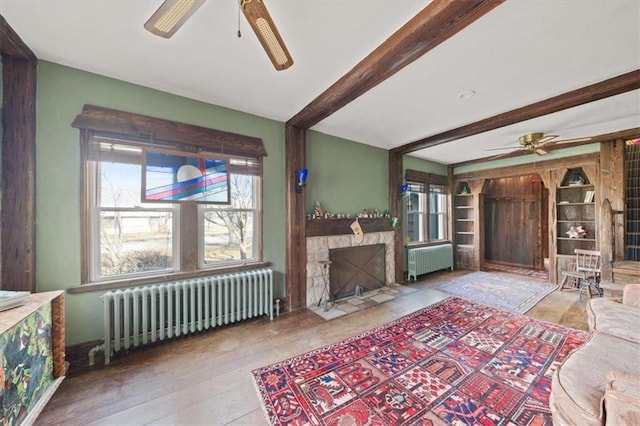 living room with beamed ceiling, wood-type flooring, and radiator